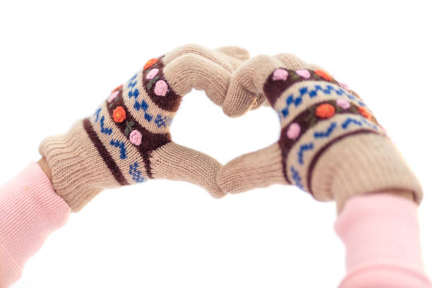 Woman hands in winters glove making heart symbol on white isolated background. \nLove and romance in the foreground. Love Winter. Concerpt for the day of all lovers.