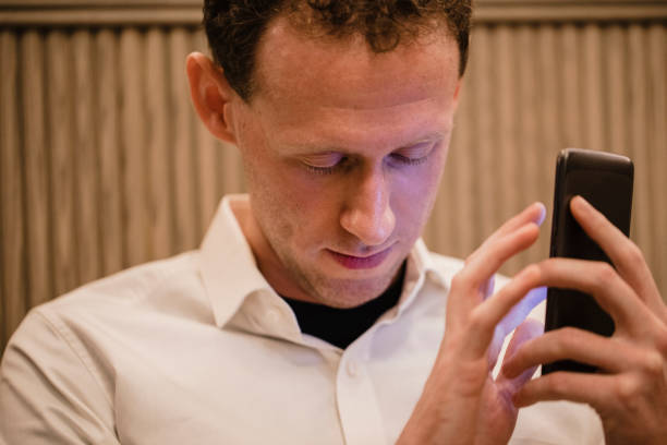 Man Using Visually Impaired App A close-up of a man wearing casual clothing, he has his smartphone in his hand and he is using a visually impaired mobile app to help assist him. assistive technology stock pictures, royalty-free photos & images
