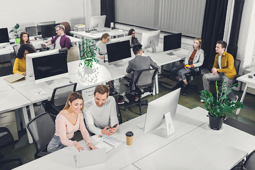 high angle view of young business colleagues sitting and working together in open space office