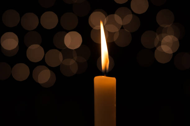 istock One candle in the dark, in the background lights 1094558476