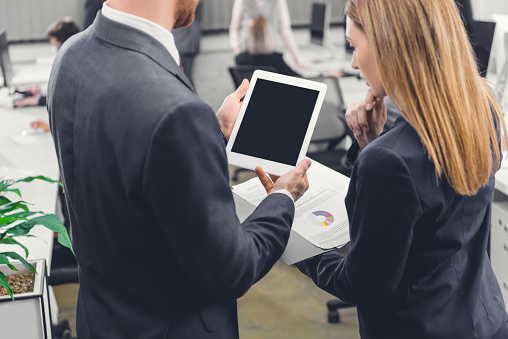 cropped shot of focused young business colleagues using digital tablet with blank screen in office