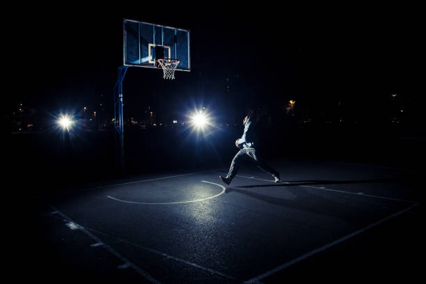 istock Young man playing basketball at night 1094561814