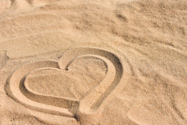 Hand drawn heart on sea sand on the beach