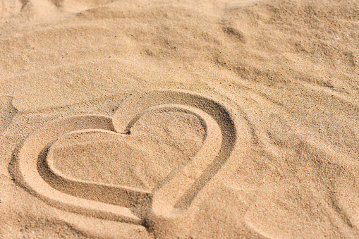 Hand drawn heart on sea sand on beach