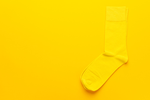 pair of socks on bright yellow background. top view of yellow socks with copy space