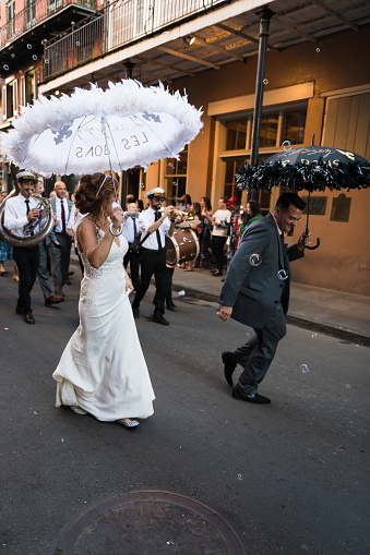 New Orleans, USA - Nov 3, 2018: A newly married bride and groom dancing through the French quarter late in the day with their own second line.