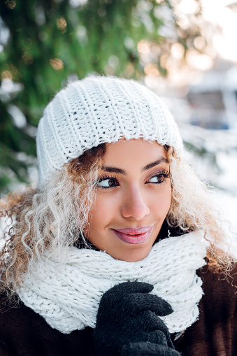 Outdoor close up portrait of young beautiful girl with afro hair in winter forest . Christmas, winter holidays concept. Snowfall.