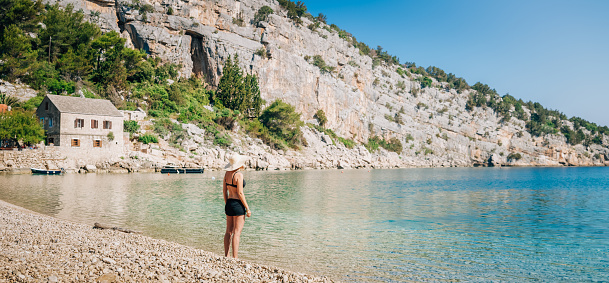 Beautiful landscape of beach in Dubrovnik,Croatia with young woman in bikini watching the horizon.