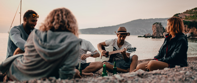 People sitting on beach while listening to guitar in Croatia