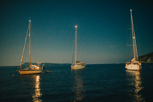 Three sailing boats floating on calm water on peaceful evening
