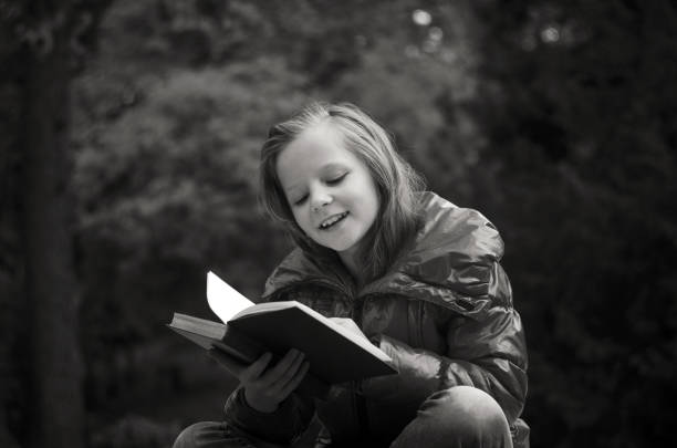 istock Happy Girl Reading Book While Sitting In Park 1094600642