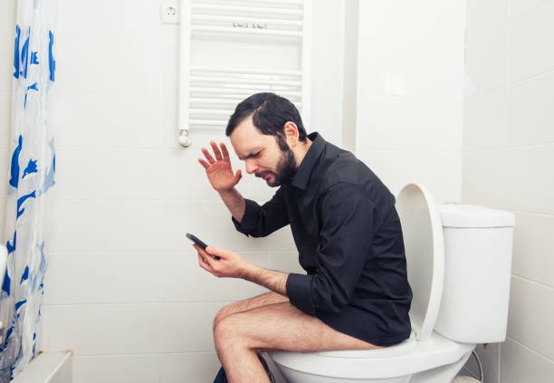 istock Side View Of Frustrated Man Gesturing While Using Smart Phone On Toilet Seat 1094601372