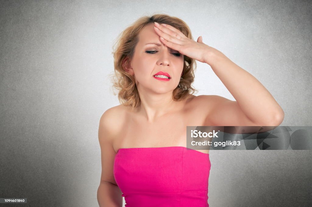 Középkorú nő rózsaszín vállon kívüli ruhában, szürke háttér előtt fejfájástól szenved - Jogdíjmentes 35-39 éves témájú stock fotó Középkorú nő rózsaszín vállon kívüli ruhában, szürke háttér előtt fejfájástól szenved - Jogdíjmentes 35-39 éves témájú stock fotó