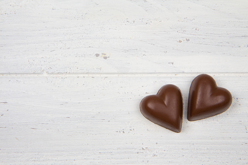 Milk chocolate on a white wooden background. Heart shaped candy. Valentine's Day
