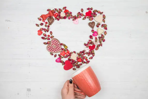 Mug in female hand. The flow of colors and decoration in the form of heart