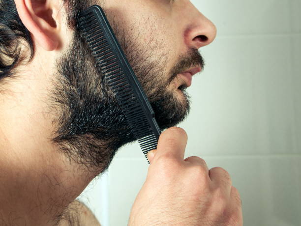 istock Close-Up Of Man Combing Beard In Bathroom 1094604600