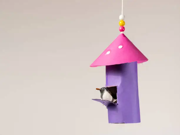 Photo of Handicraft of a colorful bird house and a small bird made of toilet paper roll