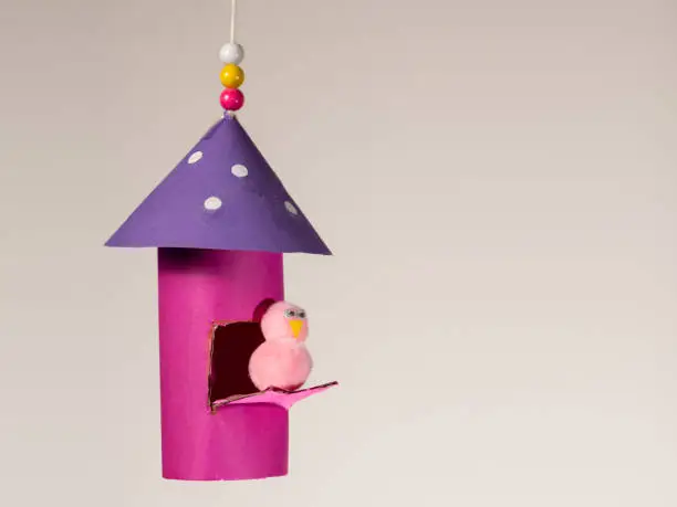 Photo of Handicraft of a colorful bird house and a small bird made of toilet paper roll