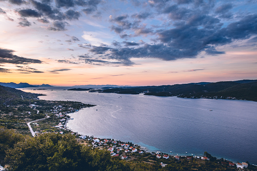 Scenic view of sea coastline with coastal town against dramatic sky at sunset, Viganj, Peljesac,Croatia