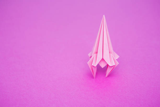 rocket from paper of origami on a pink background