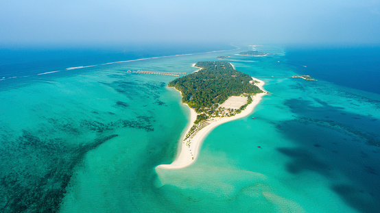 Aerial view of sandy beach and lush vegetation on tropical island surrounded by vast tranquil ocean,Maldives