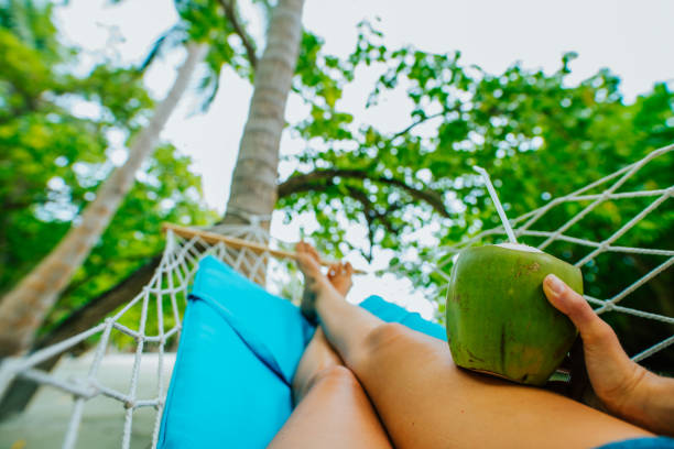 Woman drinking from coconut in hammock,Maldives