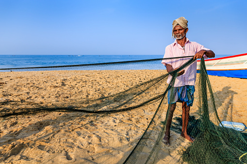 Indian fisherman at work. Fisherman are checking and repairing fishing net, Kerala, India.