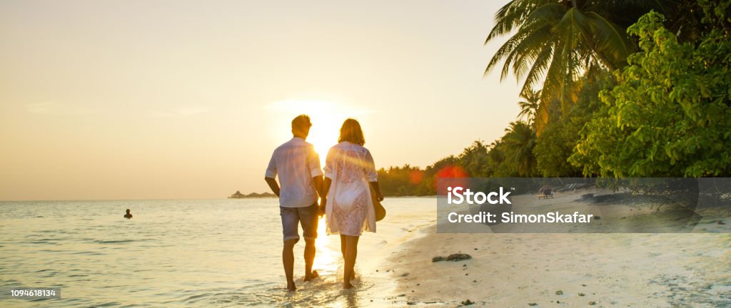 View of pair walking in water,Maldives View of pair walking in water and holding hands,Maldives Beach Stock Photo