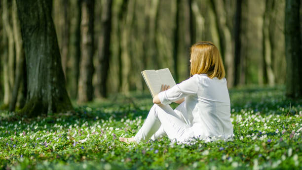 istock Woman reading book in forest 1094622990