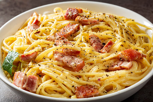 Spaghetti carbonara with pancetta, eggs and cheese in white bowl