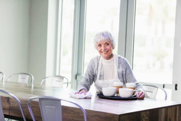 istock Senior woman working in coffee shop clearing empty table 1094631690