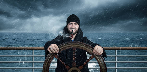 Attractive man with beard is driving the ship through rough seas Attractive man with beard is driving the ship through rough seas people laughing hard stock pictures, royalty-free photos & images