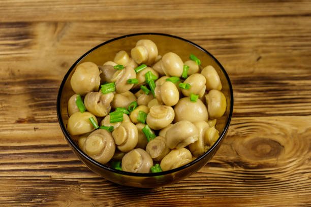 istock Glass bowl with pickled champignons. Marinated mushrooms on wooden table 1094636898