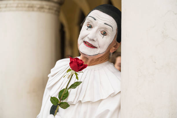 Venice, Italy - February 7, 2018: Pierrot - one old man disguised in carnival mask with red rose in his hand and with facial expression.