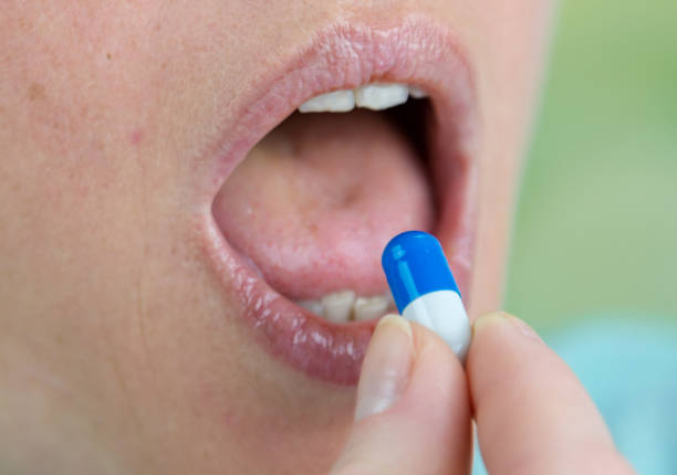 woman with red lips holding pill in mouth isolated over green Cropped image of woman with red lips holding pill in mouth isolated over green Oral medication for diabetes stock pictures, royalty-free photos & images