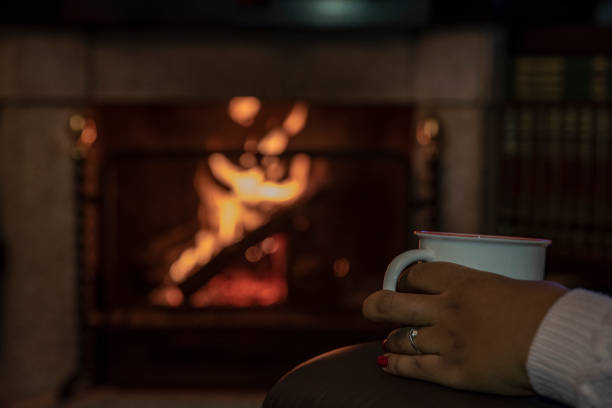 istock Woman with coffee cup by the fireplace 1094672378