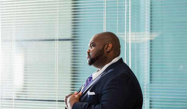 афро-американский бизнесмен с большим построить, хмурясь - overweight men suit business стоковые фото и изображения
