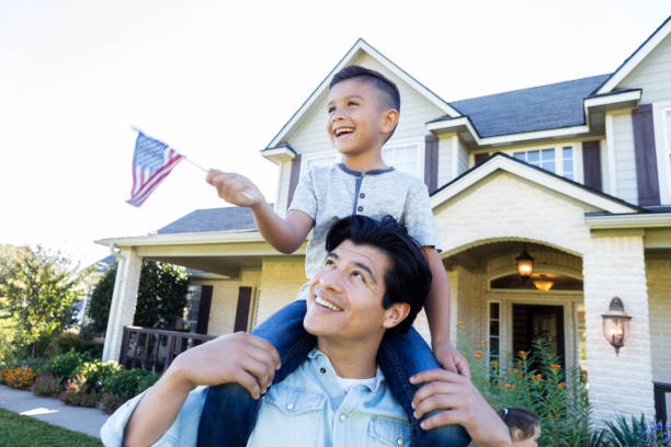 Happy boy waves American flag Cheerful little boy smiles while waving an American flag as he sits on his dad's shoulders. patriotic man stock pictures, royalty-free photos & images