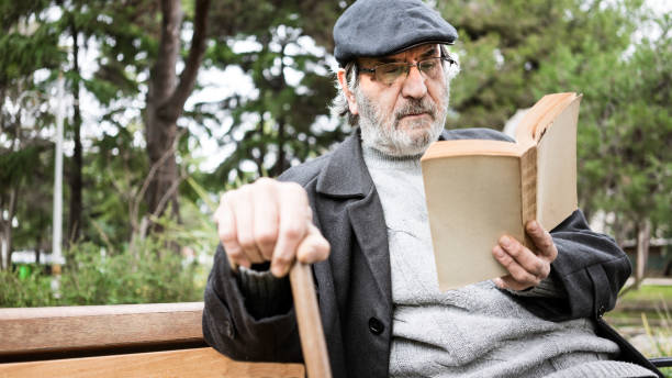 istock Old man reading book in the park 1094697056