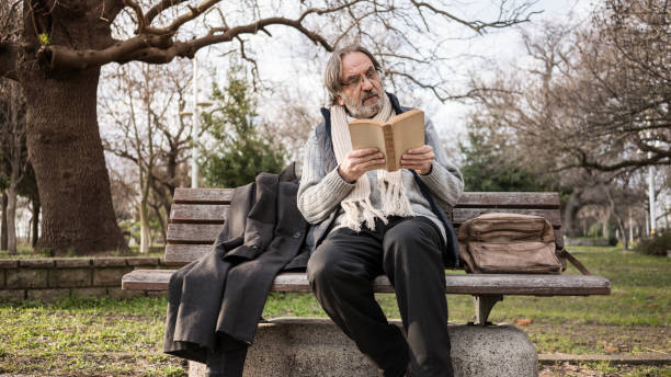 istock Old man reading book in the park 1094697170