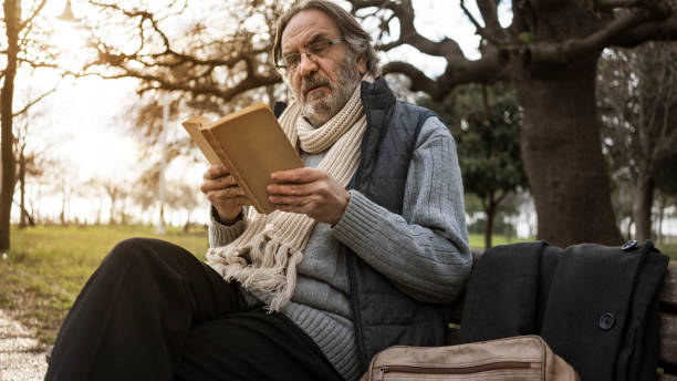 istock Old man reading book in the park 1094697188