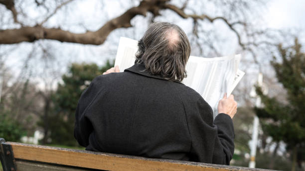 istock Old man reading newspaper in the park 1094697302