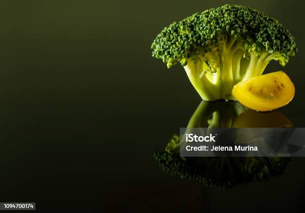 A Sprig Of Broccoli With A Slice Of Yellow Cherry Tomato Stock Photo - Download Image Now