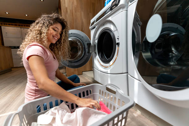 istock Latin american young client at a laundromat loading the washing machine with clothes smiling 1094713440