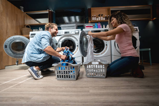 istock Friendly couple loading washing machines at the laundromat talking 1094713454
