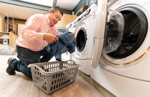 istock Cheerful customer at a laundromat loading the washing machine 1094713464