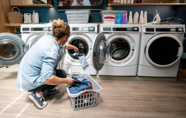 istock Backview of young man loading a washing machine at the laundromat 1094713468