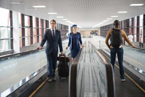 Traveling people on a moving walkway at the airport Traveling people walking at the airport on a moving walkway - travel concepts airport travelator stock pictures, royalty-free photos & images