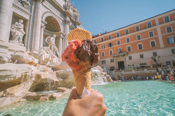 pov osobistej perspektywy ludzkiej ręki gospodarstwa gelato włoskie lody rozciągające się w kierunku fontanny di trevi w rzymie, włochy - trevi fountain rome fountain monument zdjęcia i obrazy z banku zdjęć