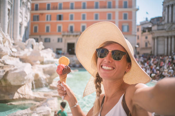 Girl with Italian gelato Ice cream taking selfie at Trevi fountain in Rome Italy Selfie portrait of young woman in Rome enjoying travel in Italy and capturing  a photo in front of the famous Trevi fountain; People travel capital in Europe concept city break photos stock pictures, royalty-free photos & images